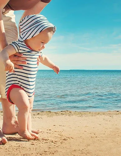 Bébé marche avec maman à la plage