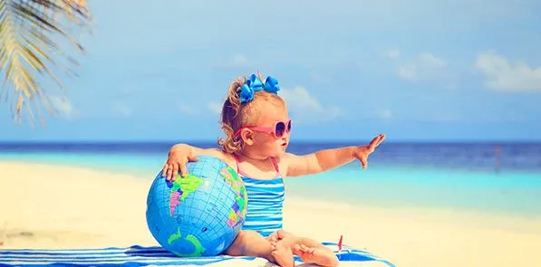 Bébé fille avec globe sur la plage